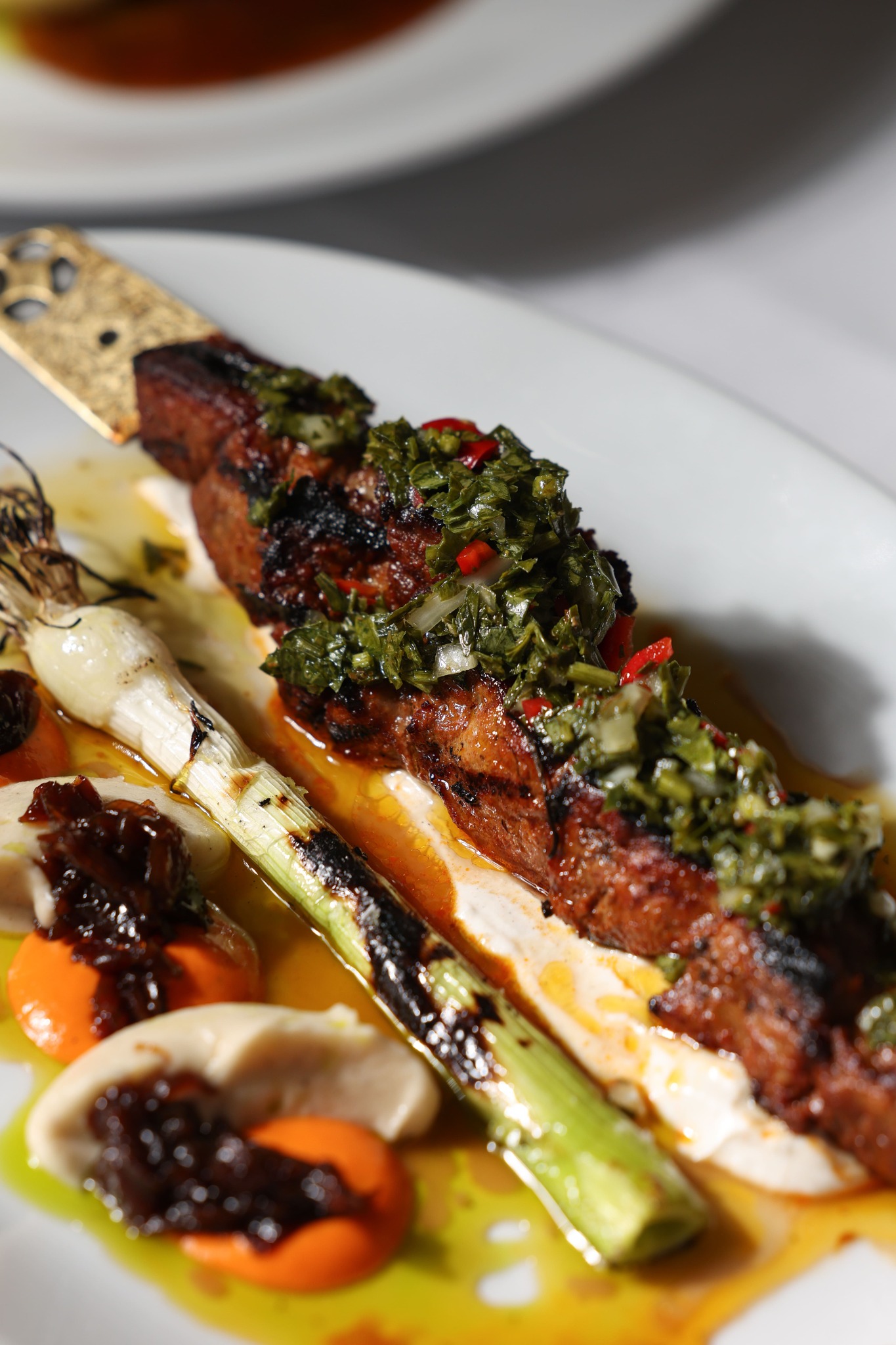 Grilled meat skewer with herbs and charred spring onion