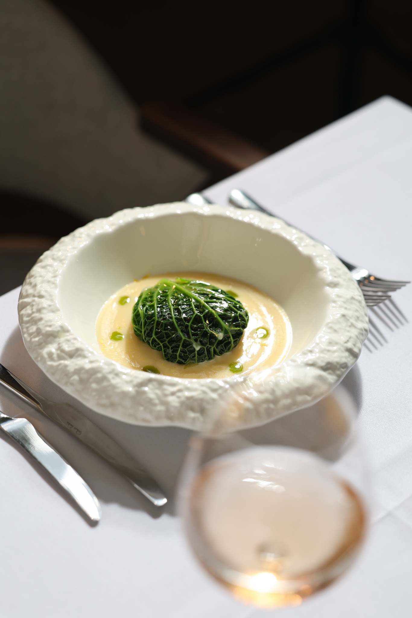 A leaf-wrapped dish in a textured white bowl with creamy sauce
